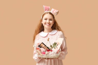 Kahverengi arka planda dekoratif kozmetiklerle dolu sepeti olan tavşan kulaklı güzel, genç bir kadın.