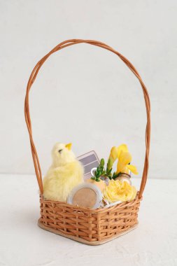 Dekoratif kozmetik ürünleri, beyaz arka planda bebek tavuk ve çiçeklerle dolu bir sepet.