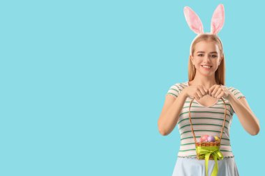 Tavşan kulaklı genç kız ve mavi arka planda Paskalya sepeti