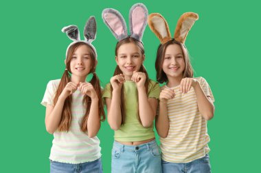 Yeşil arka planda Paskalya tavşanı kulakları olan sevimli küçük kızlar.