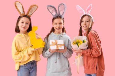 Paskalya tavşanı kulakları, çiçekleri, hediyesi ve dekoru olan sevimli küçük bir kız.