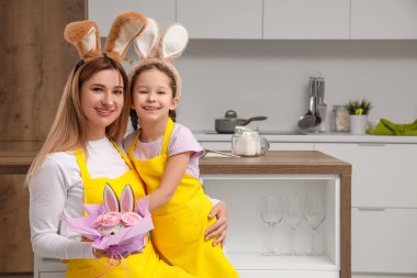 Sevimli küçük kız ve annesi mutfakta paskalya pastasıyla sarılıyorlar.