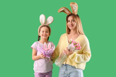 Paskalya pastalı şirin küçük kız ve yeşil arka planda tavşan kulaklı annesi.