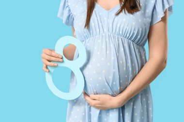 Mavi arka planda kağıttan yapılmış 8 figürlü hamile bir kadın. Uluslararası Kadınlar Günü