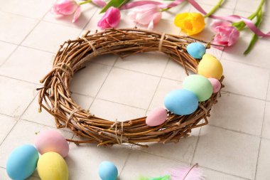 Güzel Paskalya çelengi boyalı yumurtalar ve beyaz fayanslı çiçekler.