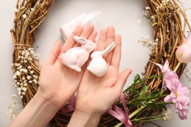 Paskalya çelengi yapan kadın, gri arka planda tavşanlar ve çiçeklerle