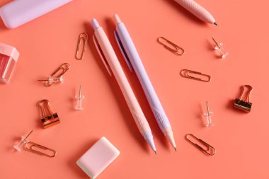 Silgiye sahip kalemler, mercan zemin üzerinde ataç ve raptiyeler