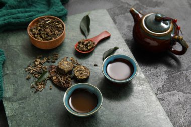 Çaydanlıklı seramik tabak ve siyah zemin üzerinde aromatik puer çayı.
