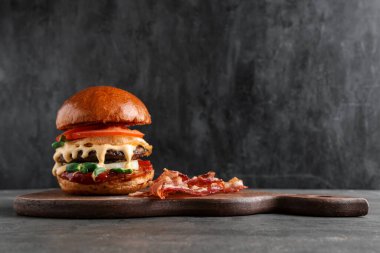 Lezzetli hamburgerli ahşap tahta ve siyah grunge arka planda pastırma.