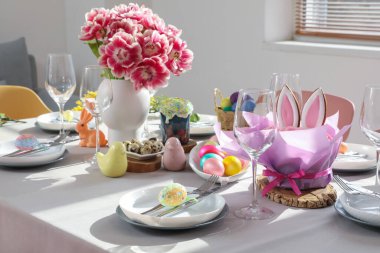Çiçekler ve boyanmış yumurtalarla süslü Paskalya sofrası.