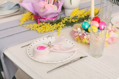 Mimoza çiçekleri, mum ve boyalı yumurtalarla güzel bir Paskalya masası.