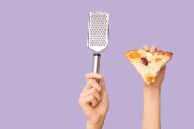 Leylak arka planında pizza dilimi ve rende tutan kadın eller.