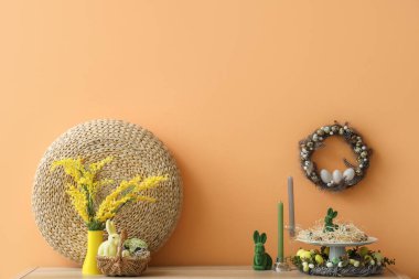 Turuncu duvarda Paskalya dekoru ve çelengi olan raflar