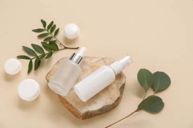 Kavanozlu kompozisyon, kozmetik ürünleri şişeleri, bej arka planda taş ve dallar
