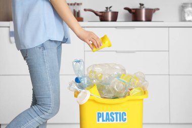 Mutfakta plastik olan çöpleri geri dönüşüm kutusuna atan kadın. Geri dönüşüm kavramı