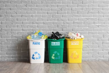 Gri tuğla duvarın yanında farklı çöp kutularıyla dolu. Geri dönüşüm kavramı