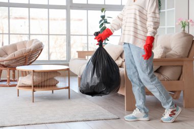 Oturma odasında çöp torbası olan kadın.