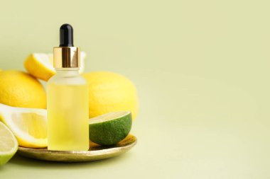 Renkli arkaplanda bir şişe temel yağ ve turunçgil meyvesi