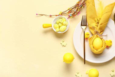 Sarı arka planda boyanmış yumurtalarla Paskalya kutlaması için güzel bir masa. Üst görünüm