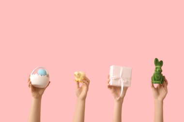 Tavşan, hediye, civciv ve pembe arka planda Paskalya yumurtası seramik sepeti olan kadın elleri.