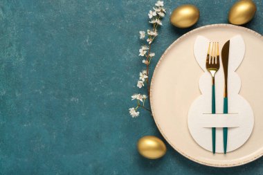 Mavi grunge arka planında Paskalya yumurtaları ve çiçek açan kiraz dallı masa ayarı