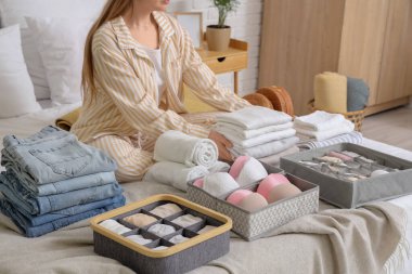 Farklı temiz elbiseli bir kadın yatakta oturuyor.