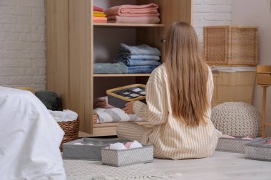 Genç bir kadın, temiz giysileri dolaba katlıyor.