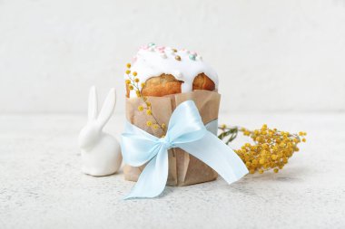 Beyaz arka planda oyuncak tavşanlı Paskalya pastası ve mimoza çiçekleri.