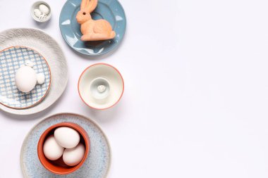Beyaz arka planda paskalya yumurtaları ve oyuncak tavşanlı masa ayarı