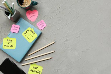Üzerinde planlar, defter ve gri arka planda bir fincan kahve olan yapışkan notlar. Yeni yıl hedefleri kavramı