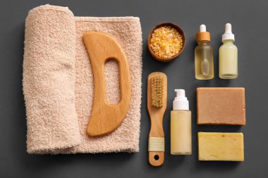 Ahşap guasha vücut masajı aracı ve siyah arka planda kozmetik ürünleri ile kompozisyon