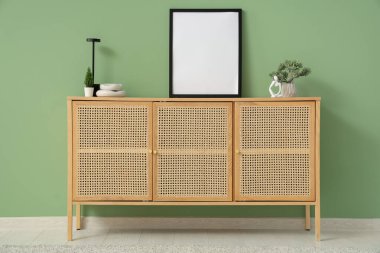 İçinde ev bitkileri olan çekmeceler ve yeşil duvarın yanındaki boş çerçeve.