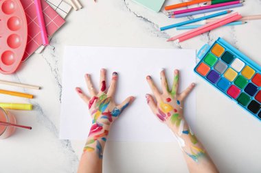 Kağıt çarşaf ve beyaz grunge arkaplan üzerine çizim için farklı kırtasiye malzemesi olan çocuk elleri