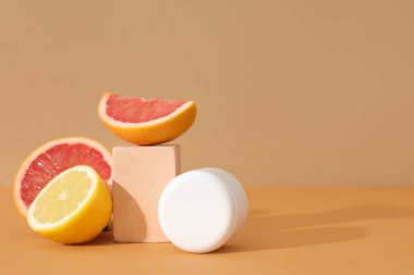 Kahverengi arka planda kozmetik ürün kavanozu, narenciye ve alçı standı ile kompozisyon