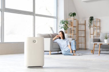 Modern nemlendirici ve genç bir kadın oturma odasında dinleniyor.