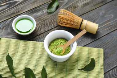 Siyah ahşap arka planda bir kase kibrit çayı ve pudra.