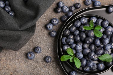 Gri arkaplanda taze yaban mersini tabağı ve tepsisi