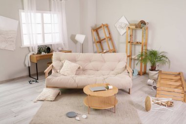 İçinde kanepe, masa ve raf üniteleri olan dağınık bir oturma odası.