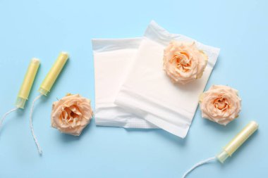 Tamponlu regl pedleri ve mavi arka planda gül çiçekleri