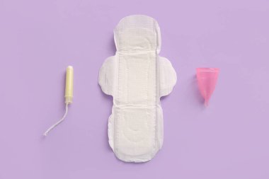 Tamponlu regl pedi ve mor arka planda fincan.