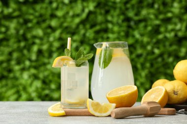 Dışarıdaki gri masada naneli taze limonata ve cam sürahi.