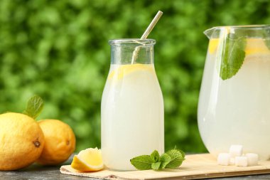 Bir şişe taze limonata ve açık havada siyah masada nane şekeri.