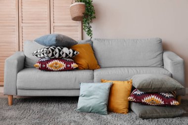 Oturma odasında bir yığın yumuşak yastıklı gri kanepe.