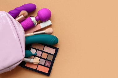 Renk arkaplanında kozmetik ürünleri ve vibratörlerle dolu çanta
