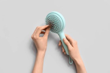 Gri arka planda fırçalı ve bir tutam saçı olan eller. Saç dökülmesi konsepti