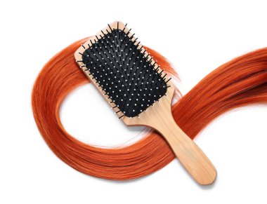 Beyaz arkaplanda saç fırçası ve kırmızı saç teli, yakın plan.