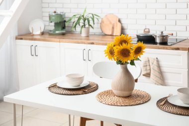 Mutfakta servis edilen yemek masasında ayçiçekli vazo.