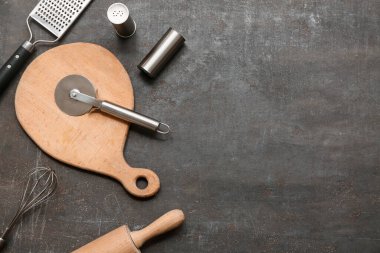 Mutfak gereçleri, paslanmaz çelik pizza keskisi ve arka planda baharatlar.