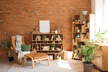 Koltuk, çekmece sandığı, kitap ve çiçeklerle dolu raf üniteleri ev kütüphanesinin içinde.