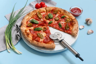 Lezzetli pizzalı kompozisyon, malzemeler ve mavi arka planda kesici.